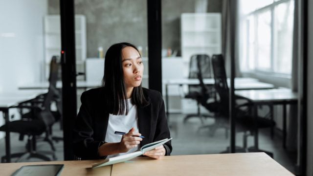 Woman writing in notebook in office setting