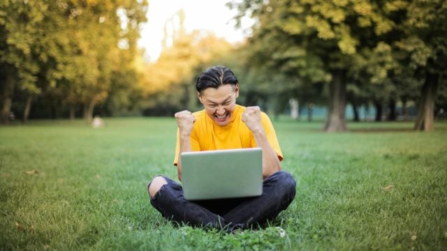 Happy man sitting outside with laptop