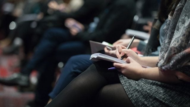 an image of a woman taking notes in a lecture