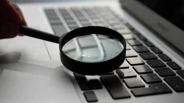 image of a magnifying glass inspecting a laptop keyboard