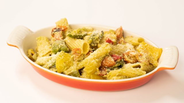 Dish of penne pasta cooked with pesto, roast vegetables and topped with Parmesan cheese.